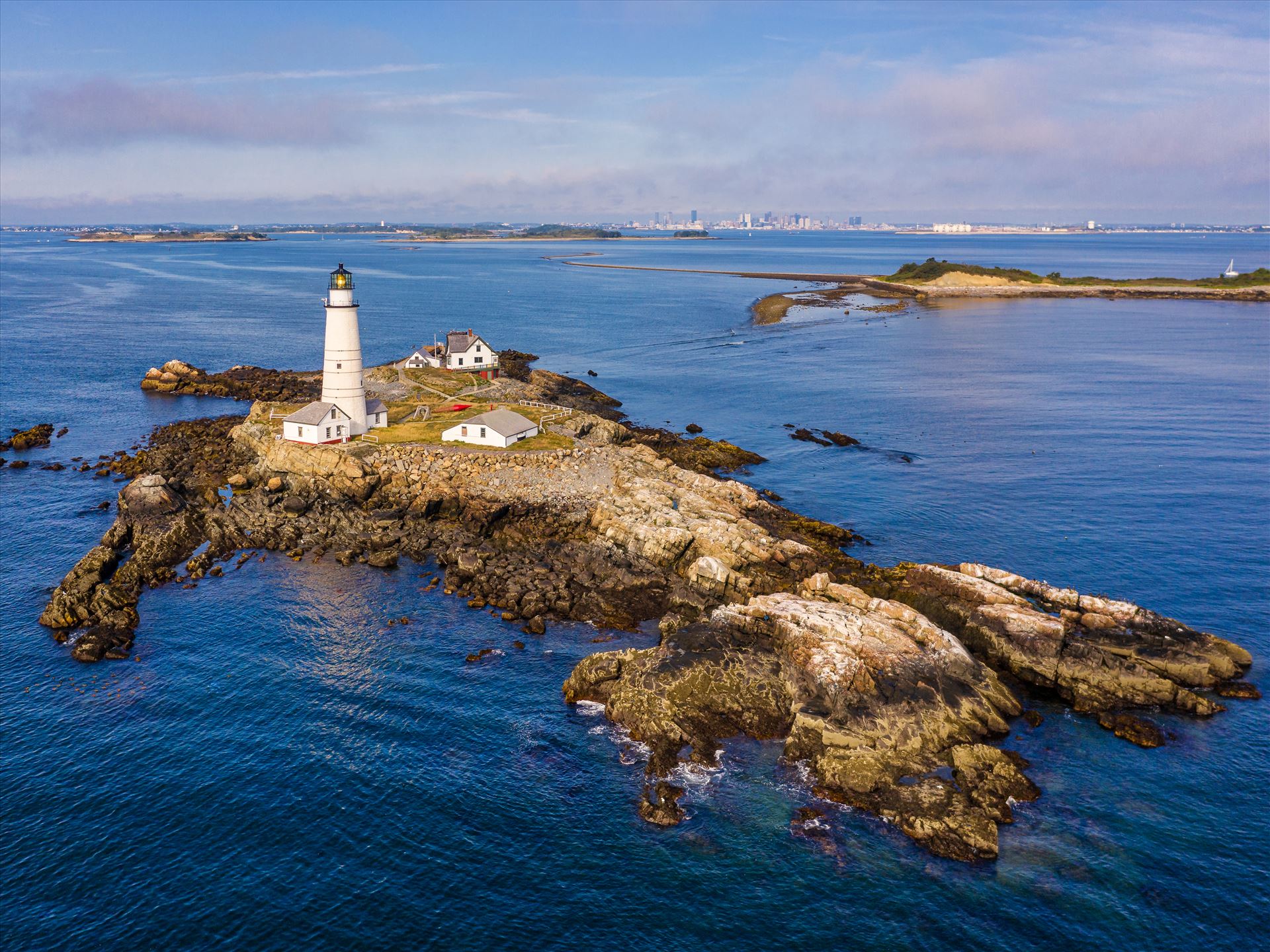 The modern Boston Harbor waterfront guarded by Boston Light, America\'s oldest lighthouse, in Boston Harbor, Boston, Massachusetts -  by New England Photography