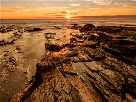 Golden sunrise illuminates a rocky outcrop near Two Lights State Park in Cape Elizabeth, Maine.
